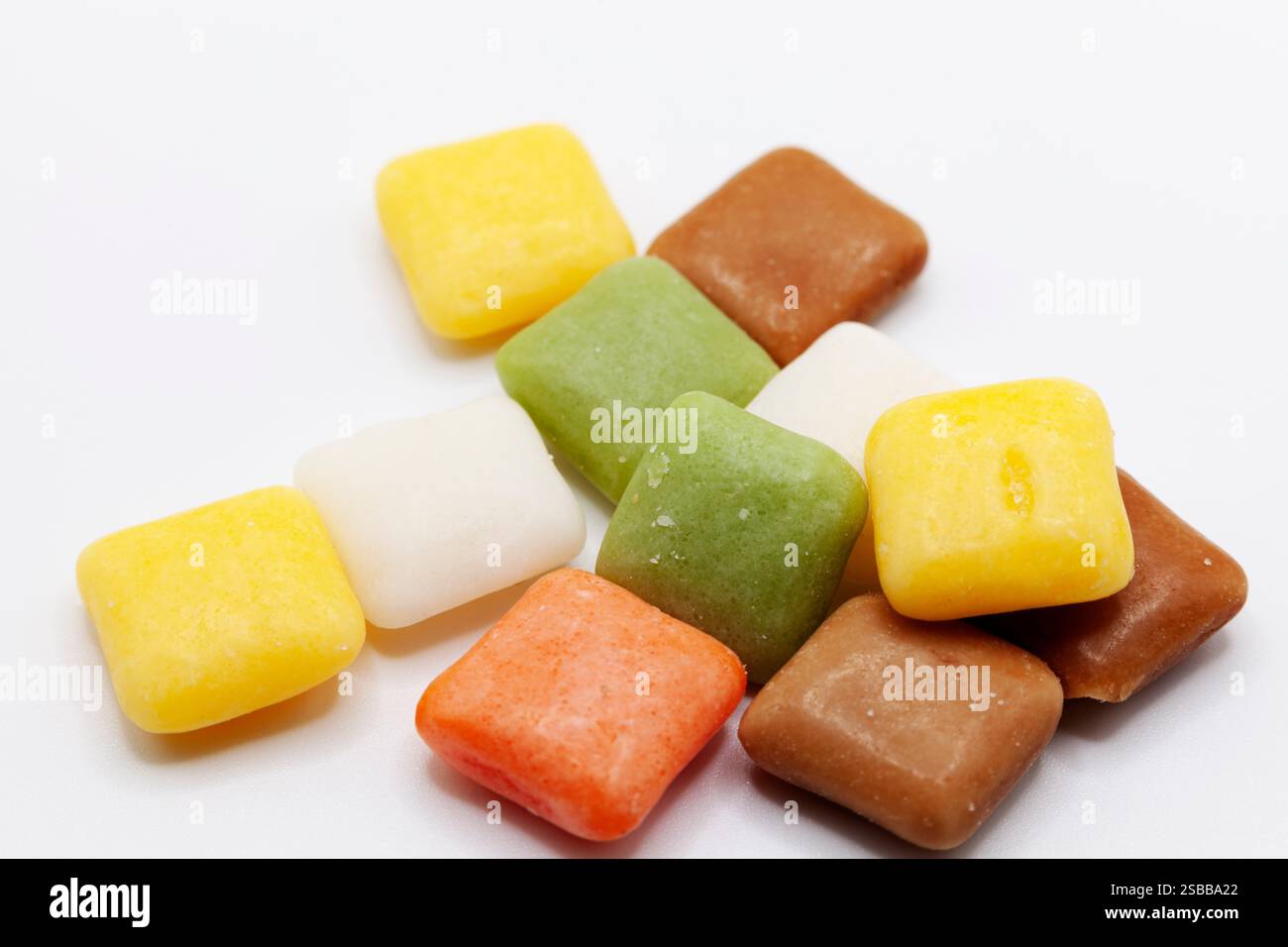 Eine Auswahl an bunten, würfelförmigen Bonbons in Gelb-, Grün-, Braun- und Orangetönen schafft ein lebendiges Mosaik süßer Leckereien. Stockfoto