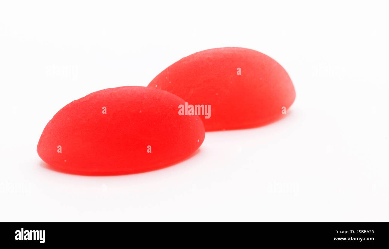 Zwei glänzend rote Bonbons mit Gummigummi stehen nebeneinander und verkörpern süße Romantik und Einfachheit. Stockfoto