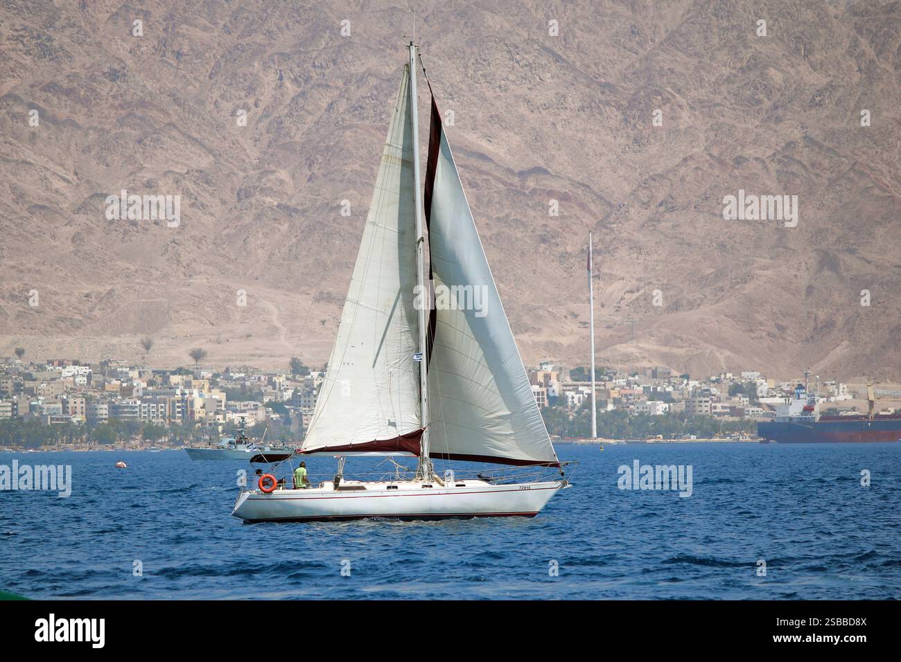 EILAT, ISRAEL - 13. MAI 2011: Die Yacht segelt entlang der im Dunst verirrten jordanischen Küste des Roten Meeres. Stockfoto EILAT, ISRAEL - 13. MAI 2011: Die Yacht segelt entlang der im Dunst verirrten jordanischen Küste des Roten Meeres. Stockfoto