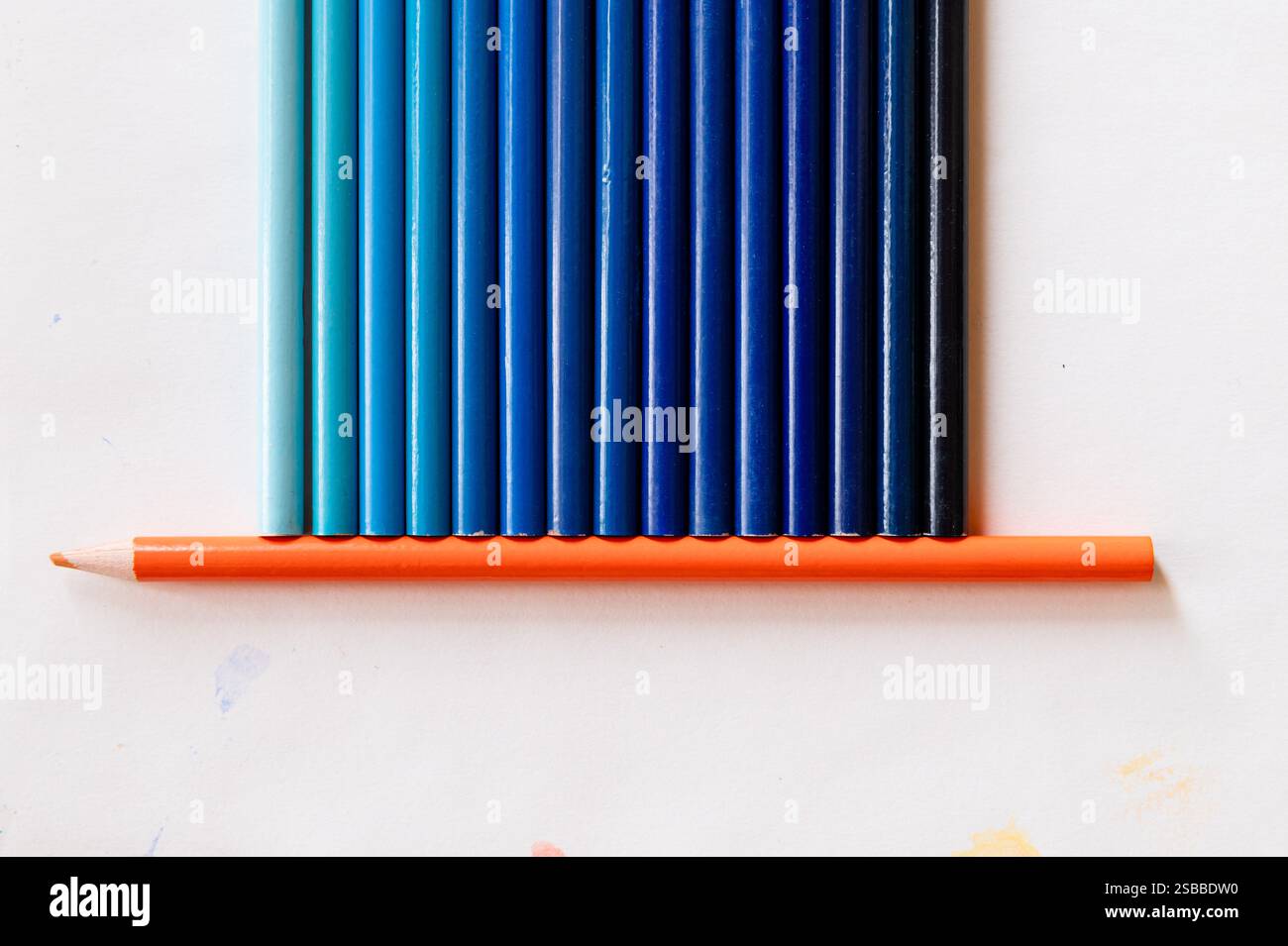 Blaue Bleistiftfarben, die auf einem orangefarbenen Bleistift sitzen Stockfoto