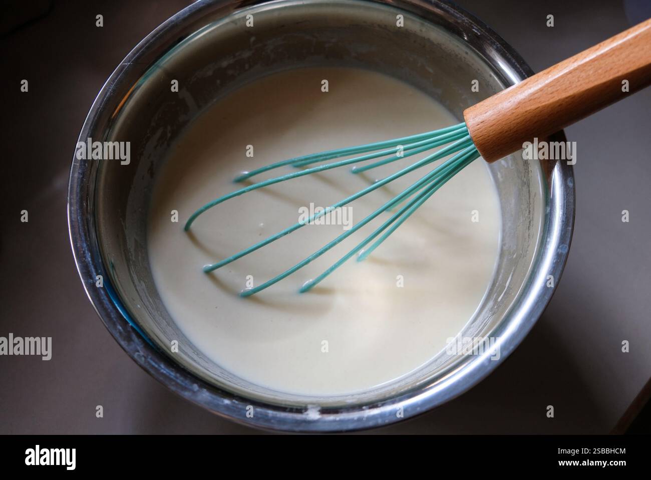 Mischen der Zutaten in einer Edelstahlschale mit dem Handquirl für die Herstellung von rissolarer Haut. Stockfoto