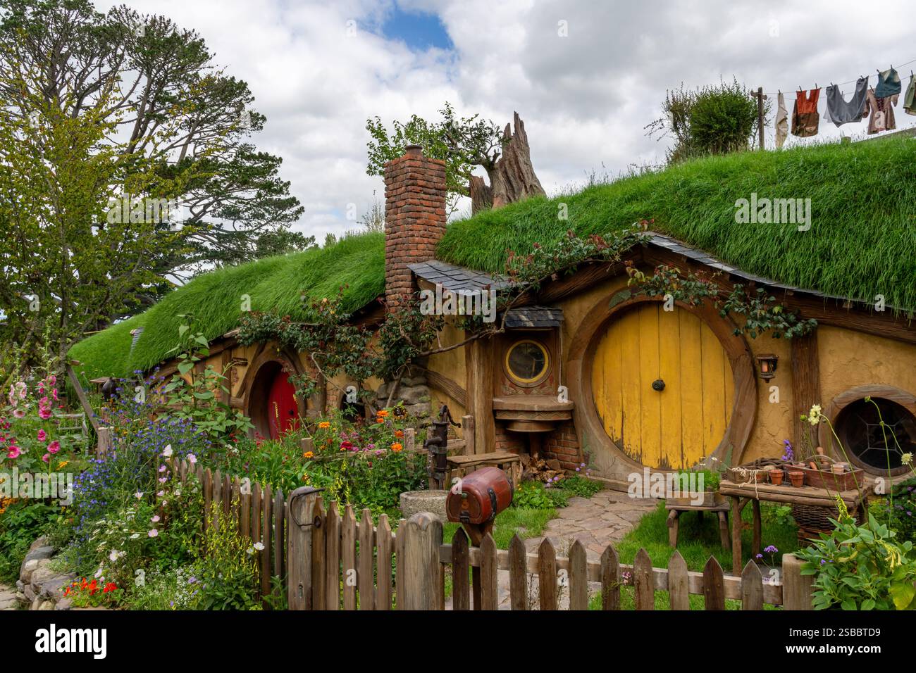 Matamata, Neuseeland - 16. Dezember 2023 Hobbit-Loch mit gelber Tür und Garten Stockfoto