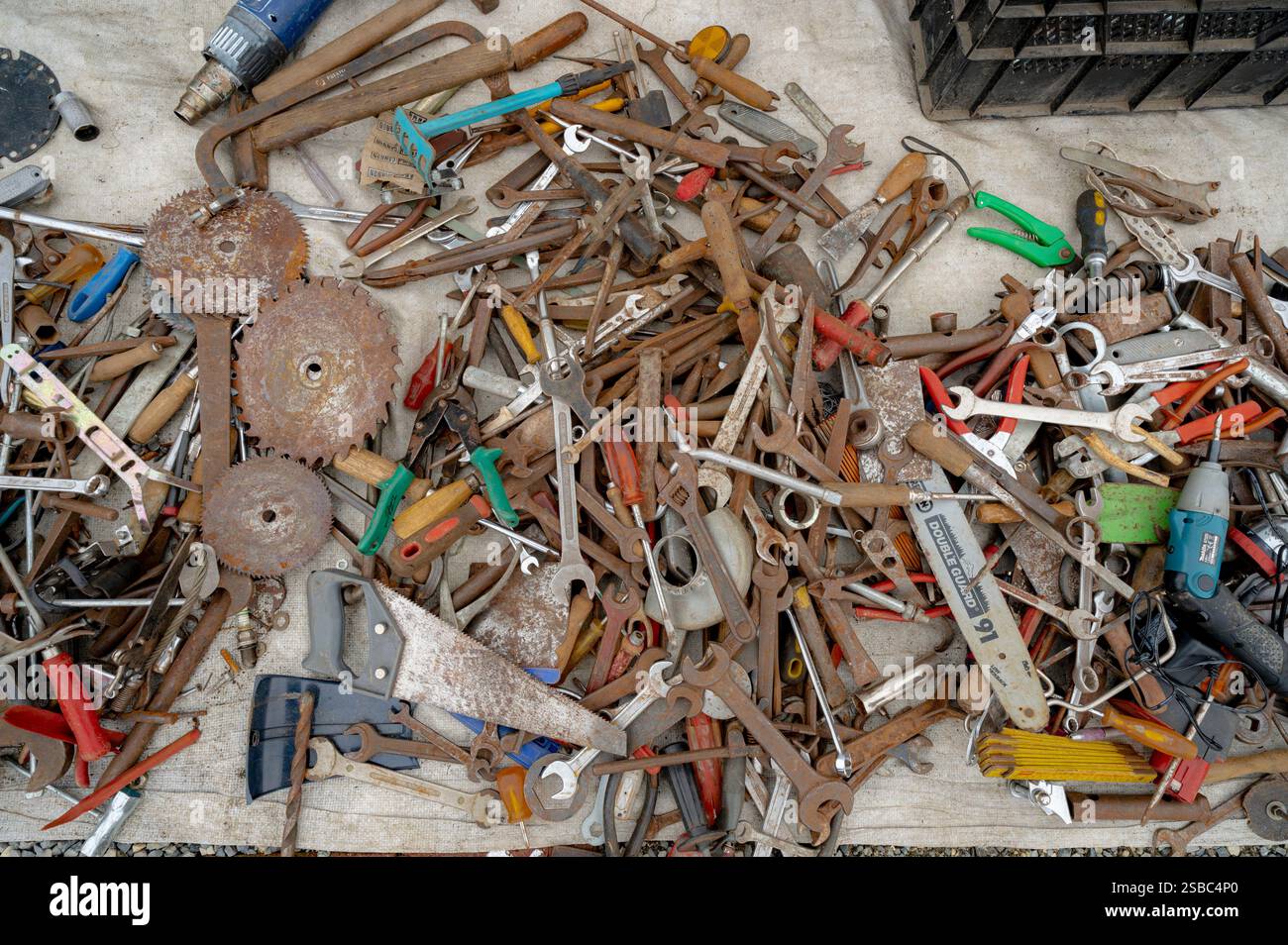 Hunedoara, Rumänien - 25. Januar 2025: Menschenmenge und verschiedene Gegenstände, Spielzeug, Werkzeuge und Elektronik auf einem Flohmarkt. Stockfoto