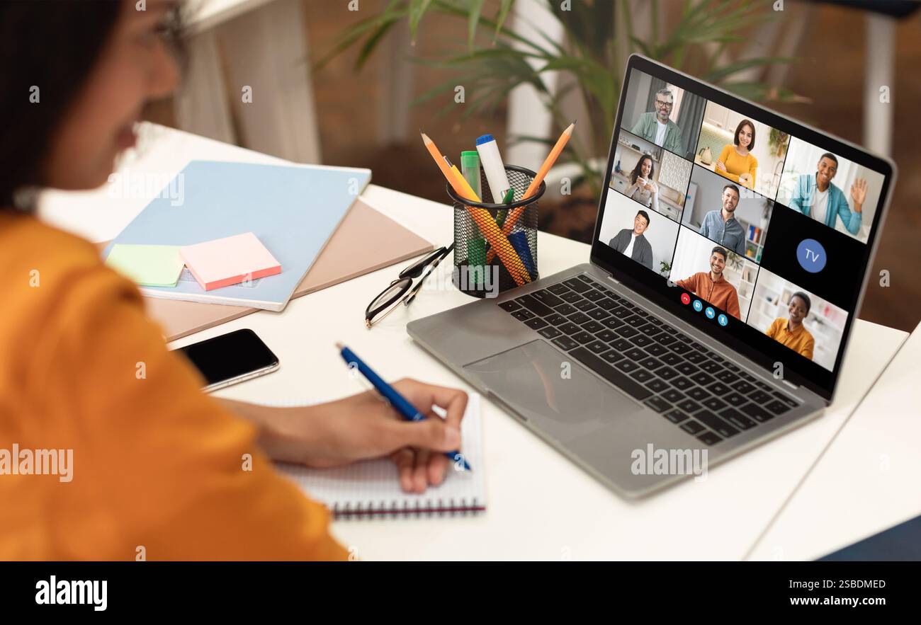Frau macht Notizen während einer Videokonferenz auf einem Laptop Stockfoto