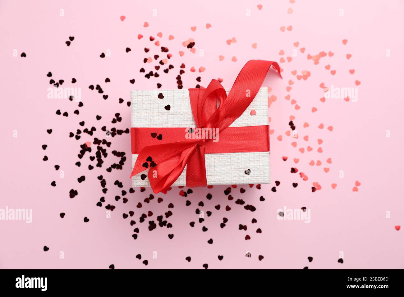 Romantisches Geschenk und Konfetti auf hellrosa Hintergrund, Draufsicht Stockfoto