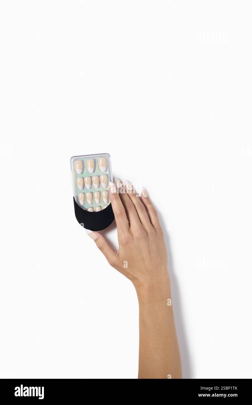 Frauenhand mit falschen Nägeln nach Nagelstudio auf weißem Hintergrund. Falsche oder falsche Nägel mit Beschneidungspfad. Kunstnageldesign an den Fingern. Stockfoto