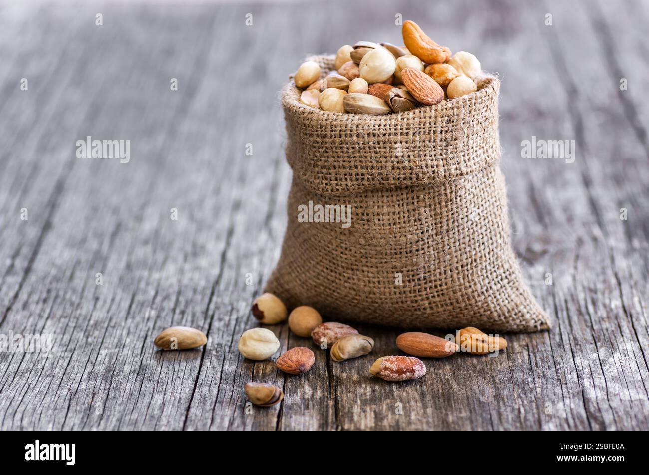 Gemischte Nüsse, getrocknete Früchte auf rustikalem Tisch, verschiedene Art von gesundem Essen Stockfoto