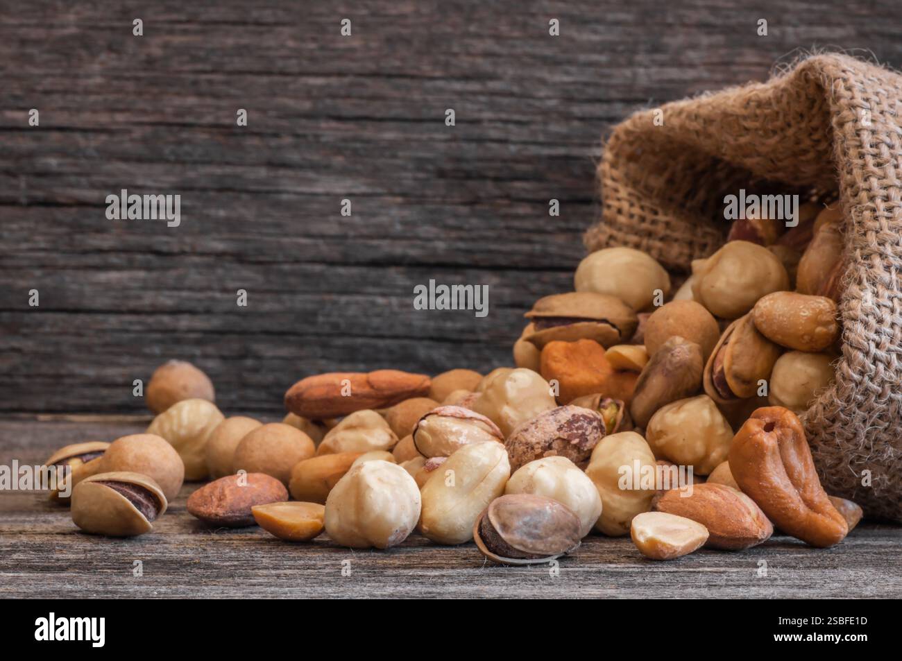Gemischte Nüsse, getrocknete Früchte auf rustikalem Tisch, verschiedene Art von gesundem Essen Stockfoto