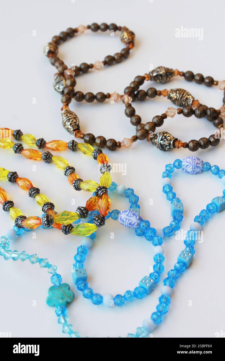Perlenketten mit braunen, blauen und gelben Perlen. Stilvolle Modeaccessoires, Modeschmuck, handgemachte Bijouterie auf vertikalem weißem Hintergrund. Stockfoto