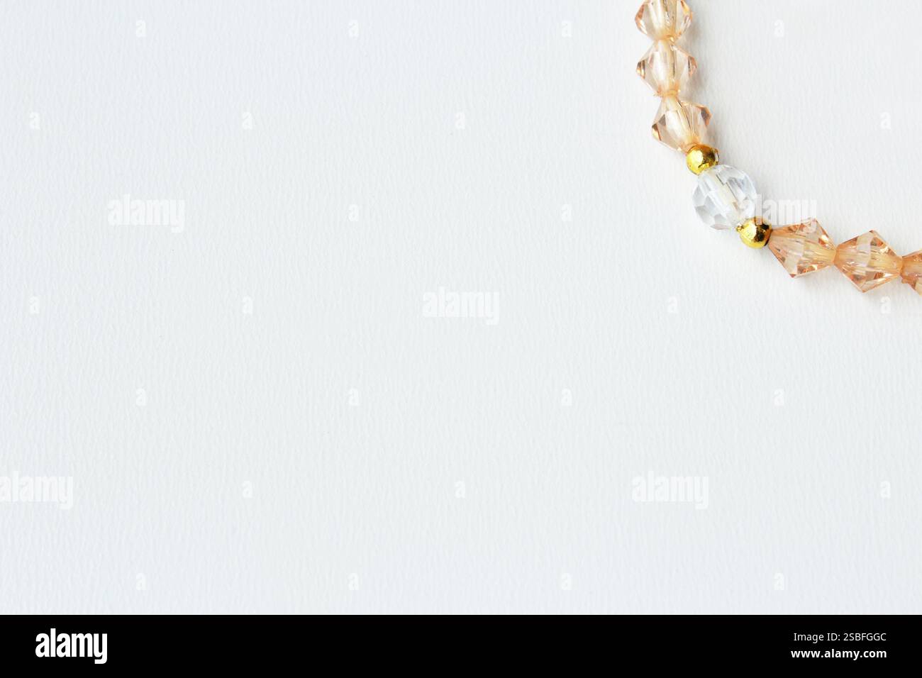 Sauberer und minimalistischer Bannerhintergrund mit Kopierraum und elegantem Perlenstrang in ambar-Farbe an der rechten oberen Ecke. Ideal für High-End-Modeschmuck Stockfoto