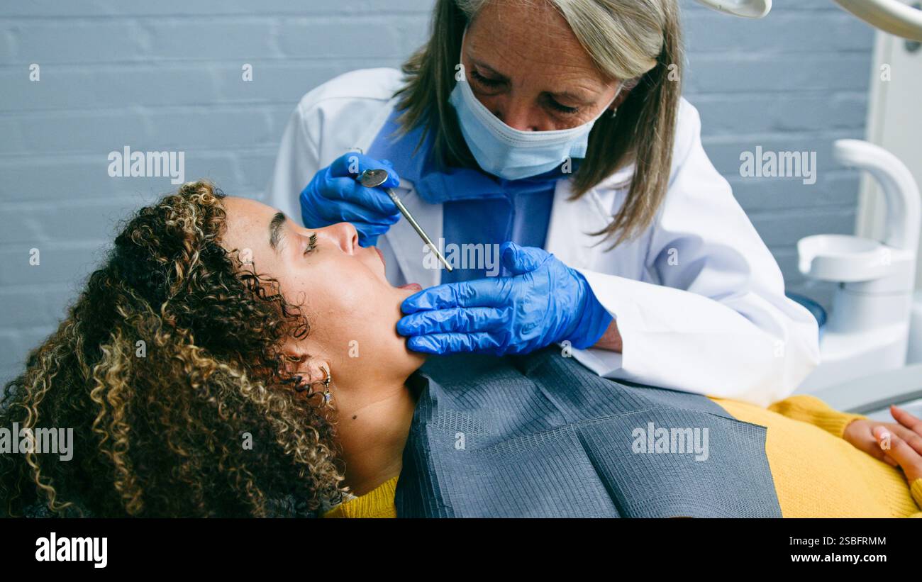 Ein spezieller Zahnarzt führt Routine-Checkup für einen ruhigen Patienten in einer professionellen Zahnarztpraxis durch Stockfoto