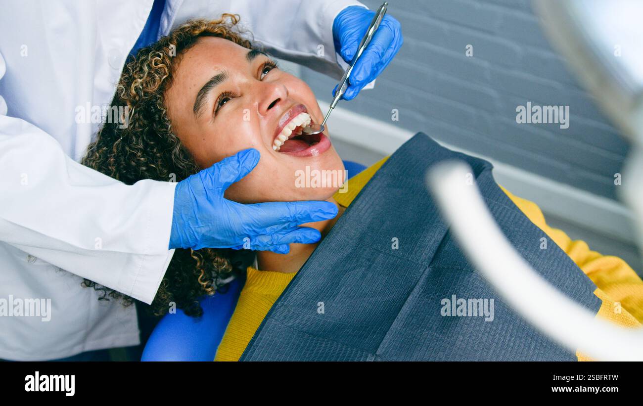 Lächelnder Patient, der während einer Routineuntersuchung im klinischen Umfeld zahnärztlich versorgt wird Stockfoto