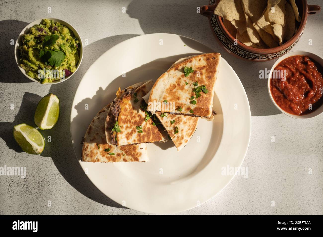 Quesadillas aus schwarzen Bohnen mit Guacamole, Salsa und Tortillachips Stockfoto