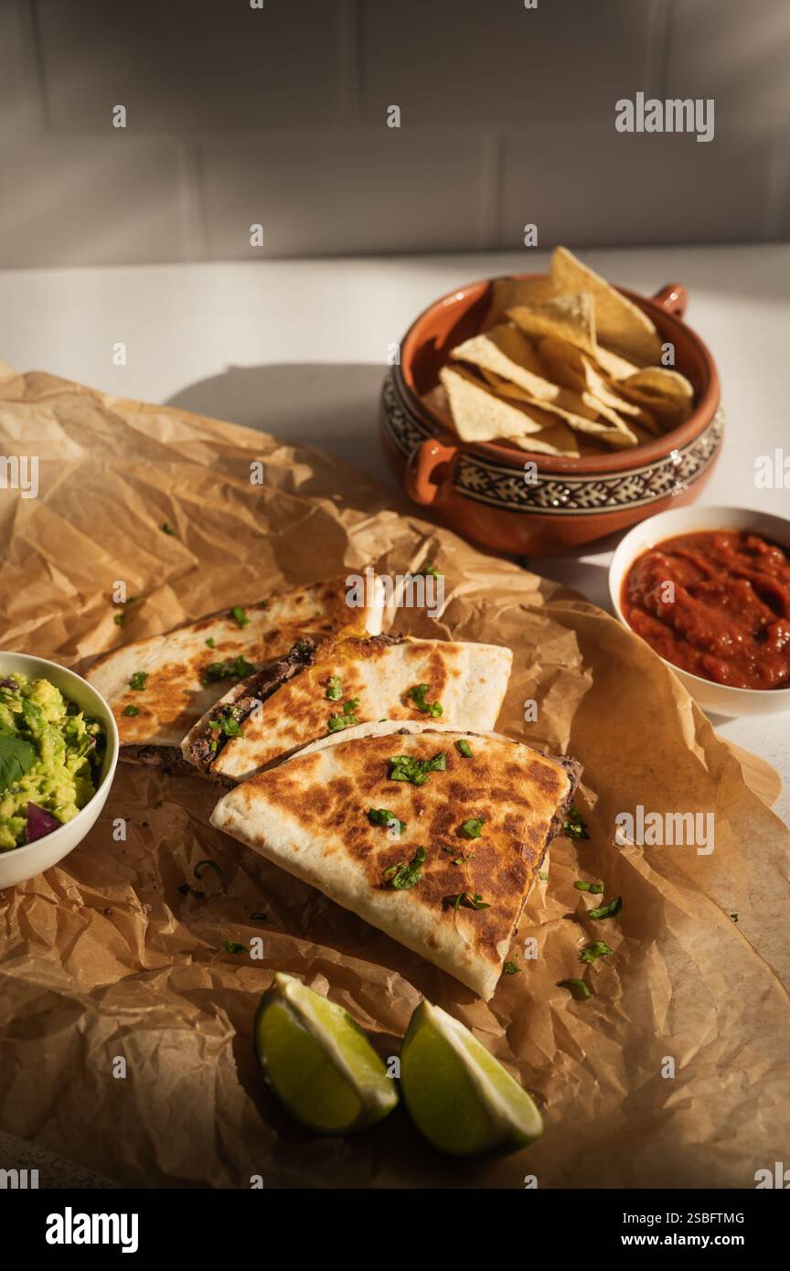 Pürierte Quesadillas aus schwarzen Bohnen mit Guac, Salsa und Tortillachips Stockfoto