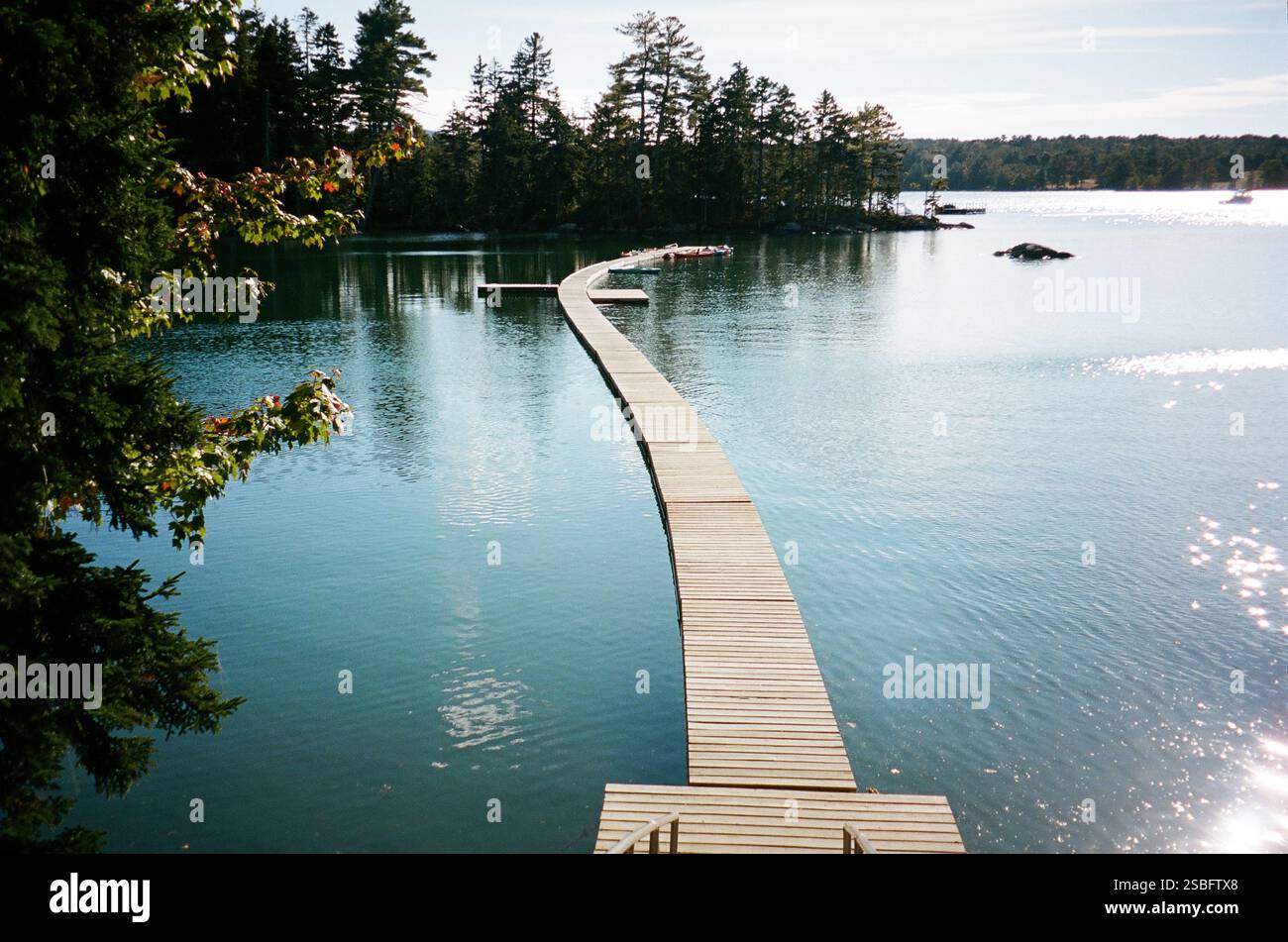 Dock führt zu farbenfrohen Kajaks, die auf einem ruhigen See schwimmen Stockfoto
