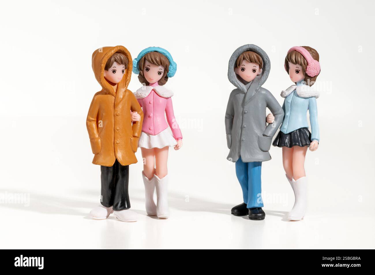 Miniatur-Freunde und -Freundinnen gehen Arm in Arm zusammen und tragen Winterkleidung Stockfoto