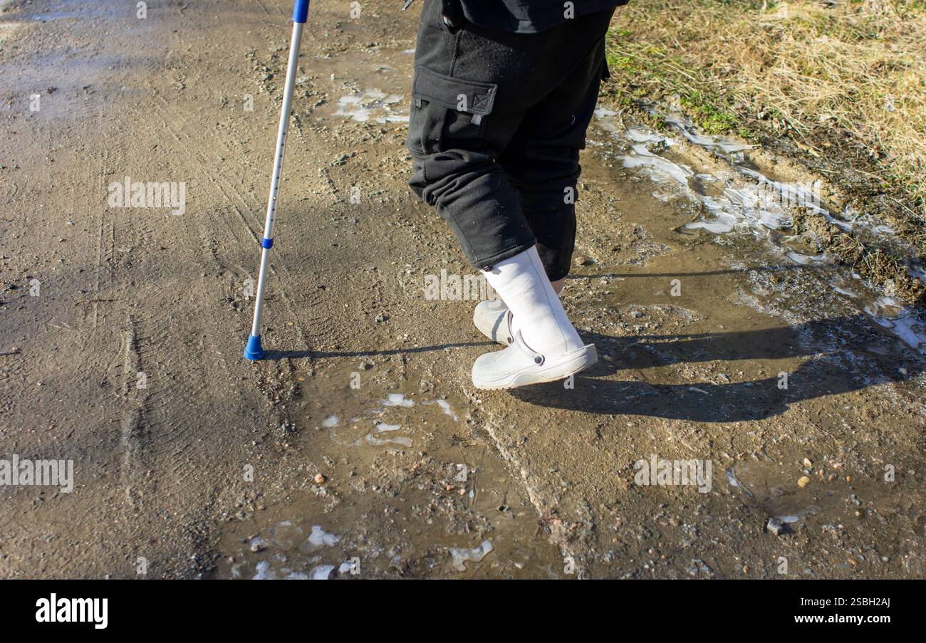 Alter Mann mit Gehhilfe im Winter auf schwarzem Eis, Rutschgefahr Stockfoto