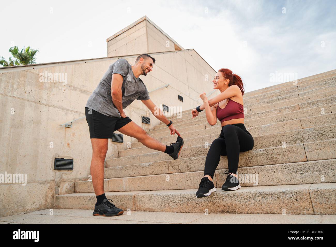 Ein dynamisches Paar, das gemeinsam Dehnungsübungen macht und seine Trainingsroutine genießt. Sie teilen freudige Motivation und Unterstützung, während sie gemeinsam mit Enthusiasmus auf ihre Fitnessziele hinarbeiten. Hochwertige Fotos Stockfoto