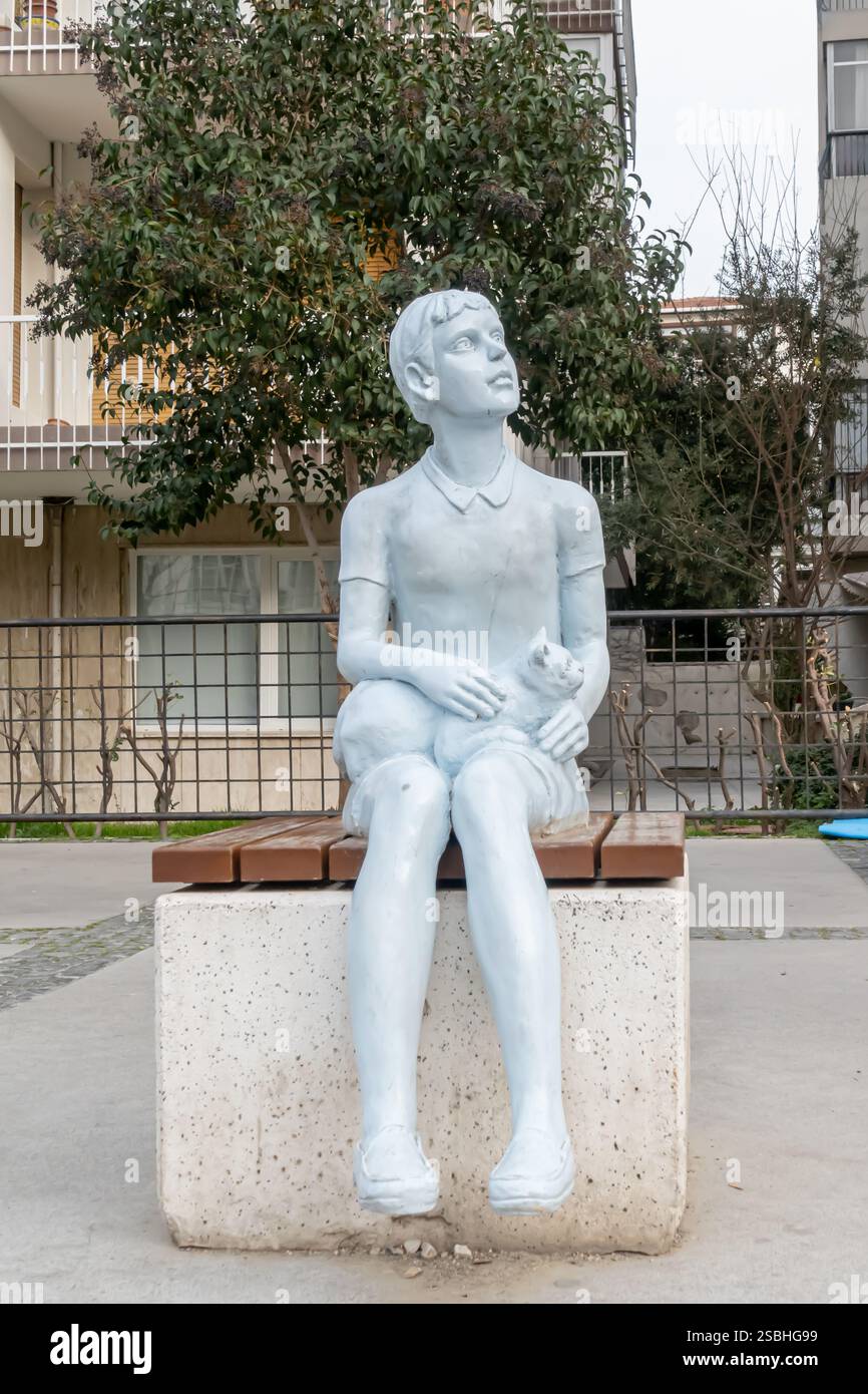 Stadtskulptur - ein junger Mann, der mit einer Katze auf einer Bank sitzt, Izmir, Türkei Stockfoto