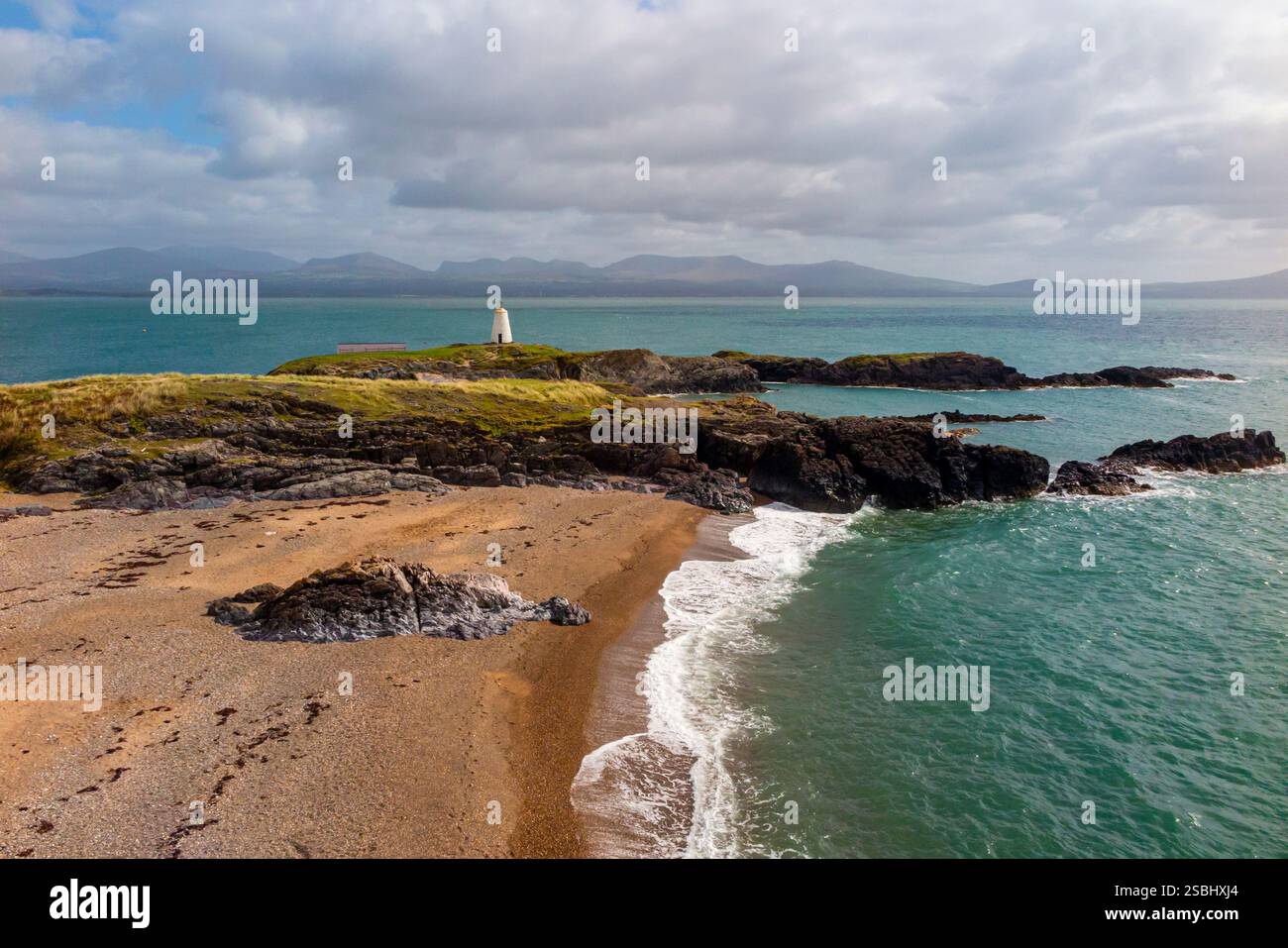 Die Berge von Snowdonia im Hintergrund und das Meer der Menai-Straße von Ynys Llanddwyn vor der Küste von Anglesey in Nordwales Großbritannien Stockfoto
