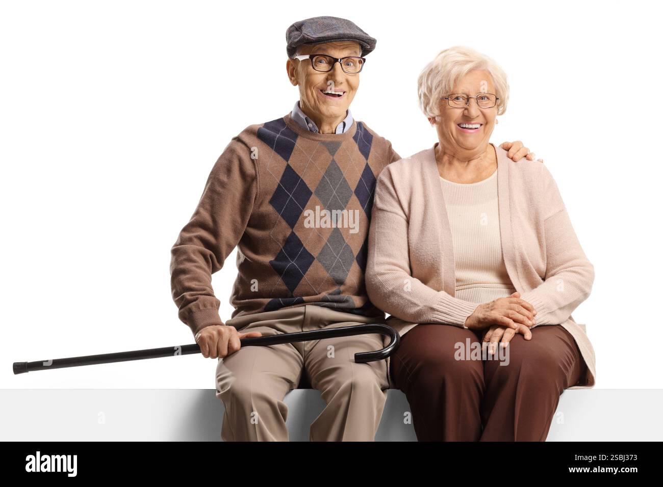 Älteres Paar sitzt auf einer leeren Tafel und lächelt in die Kamera isoliert auf weißem Hintergrund Stockfoto