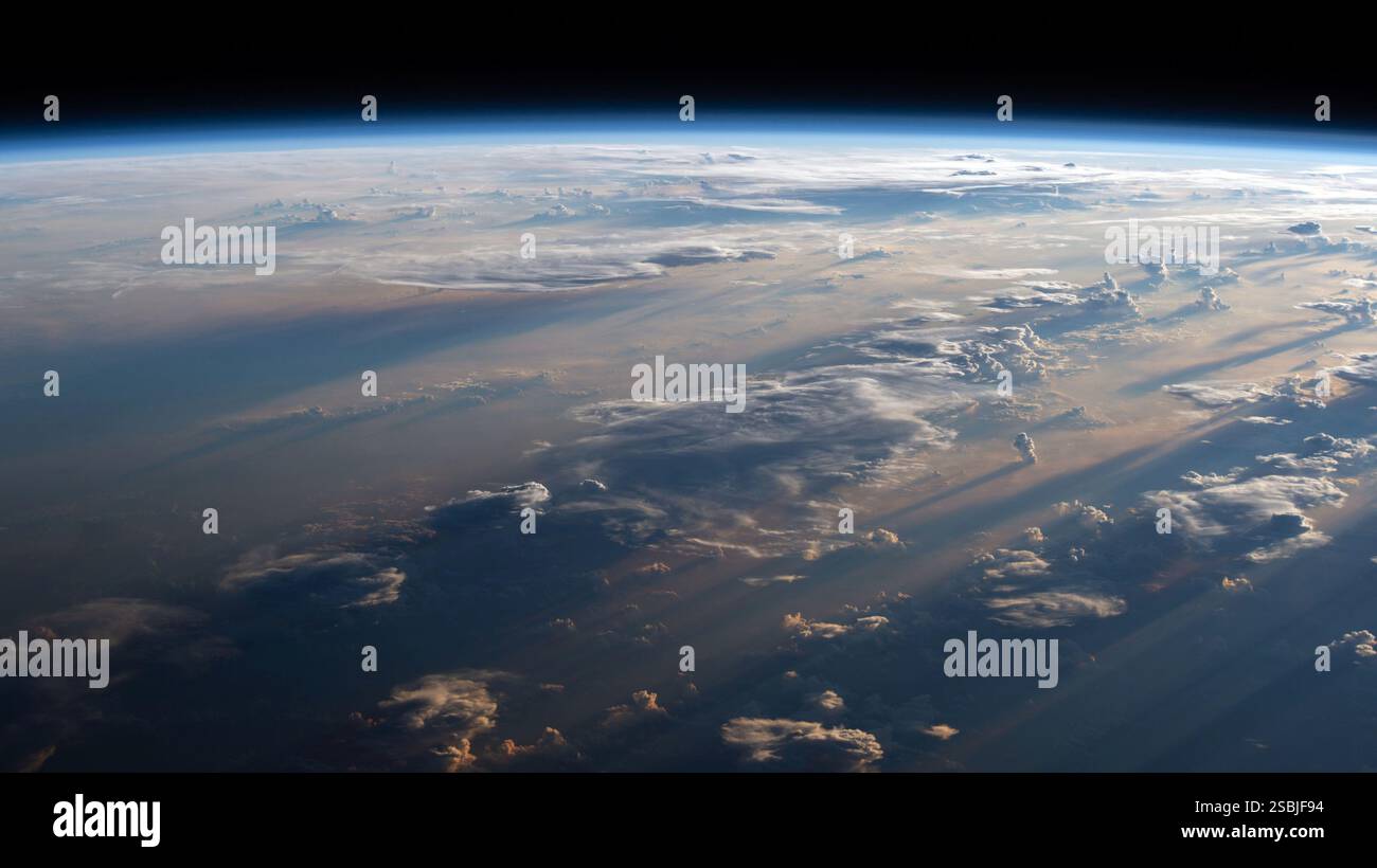 Der Sonnenaufgang wirft lange Schatten über das bewölkte Philippinische Meer in dieser Satellitenansicht von der Internationalen Raumstation. Stockfoto