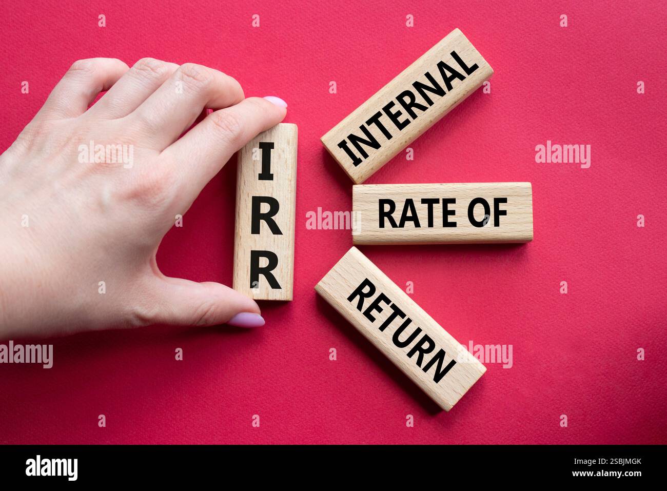 IRR – Symbol für interne Rückkehrrate. Konzeptwort IRR auf Holzwürfeln. Geschäftsmann Hand. Schöner roter Hintergrund. Business und IRR-Konzept. Spa kopieren Stockfoto
