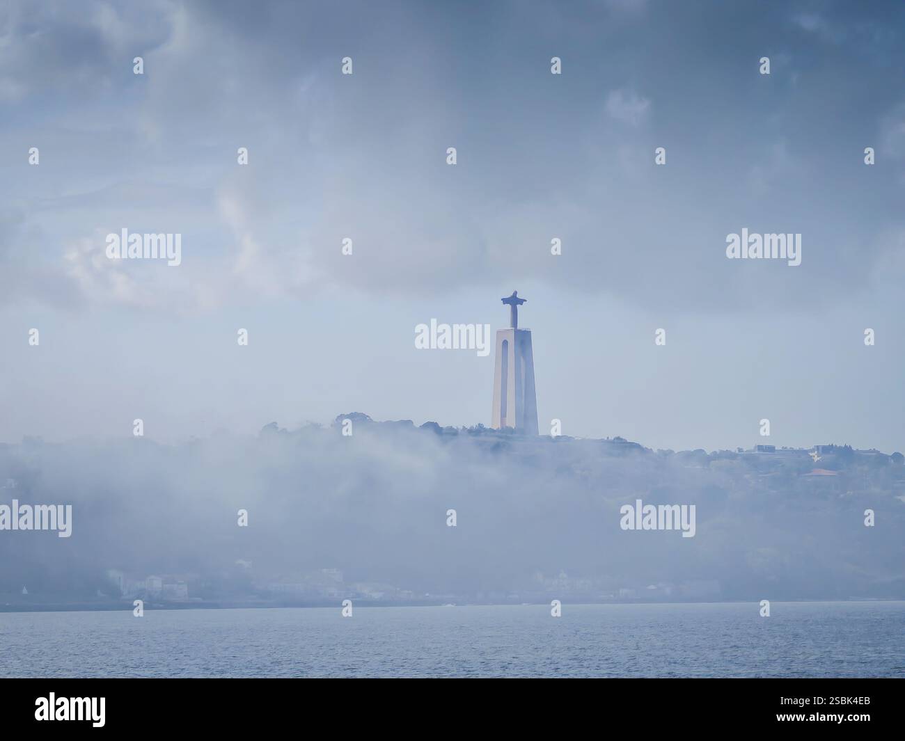 Cristo-Rei-Statue im Nebel neben der Brücke vom 25. April in der Nähe des Tejo-Flusses. Heiligtum Christi des Königs an einem bewölkten Tag Stockfoto