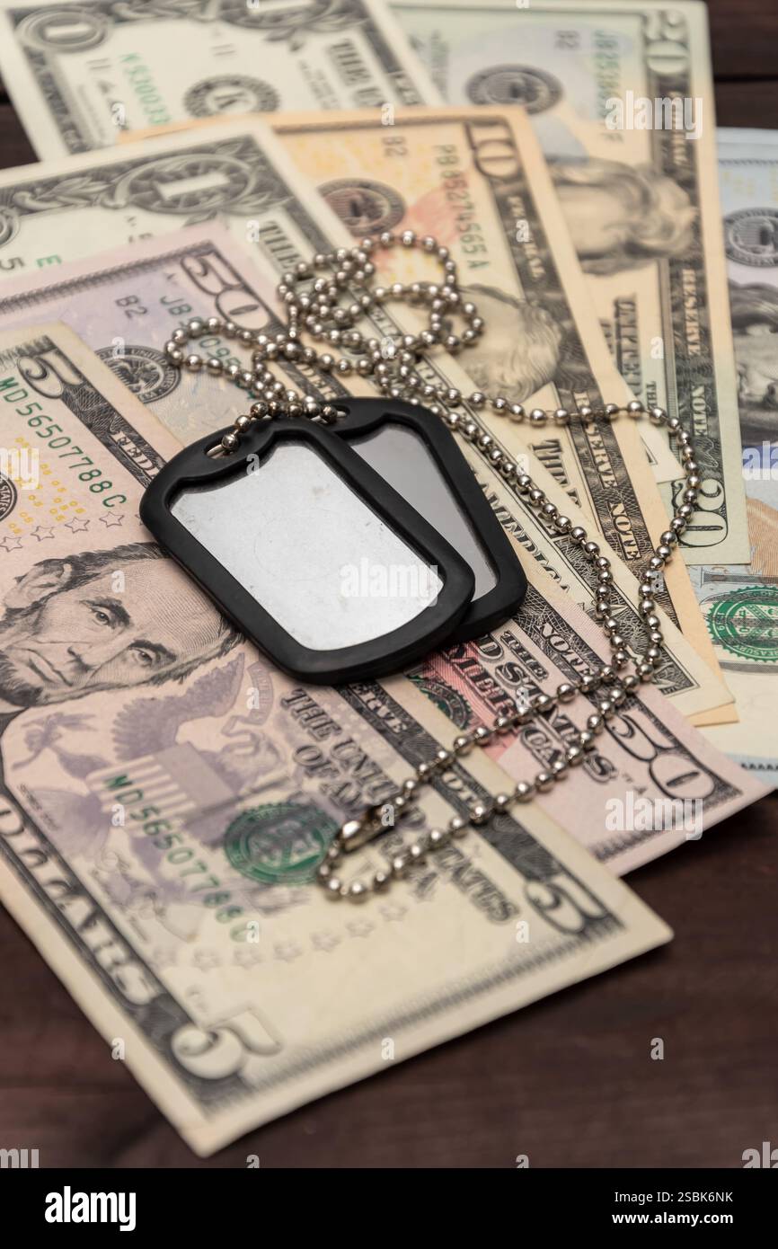 Ein Militärabzeichen vor dem Hintergrund verstreuter Dollars symbolisiert die Kosten für Dienst und Militärlohn Stockfoto