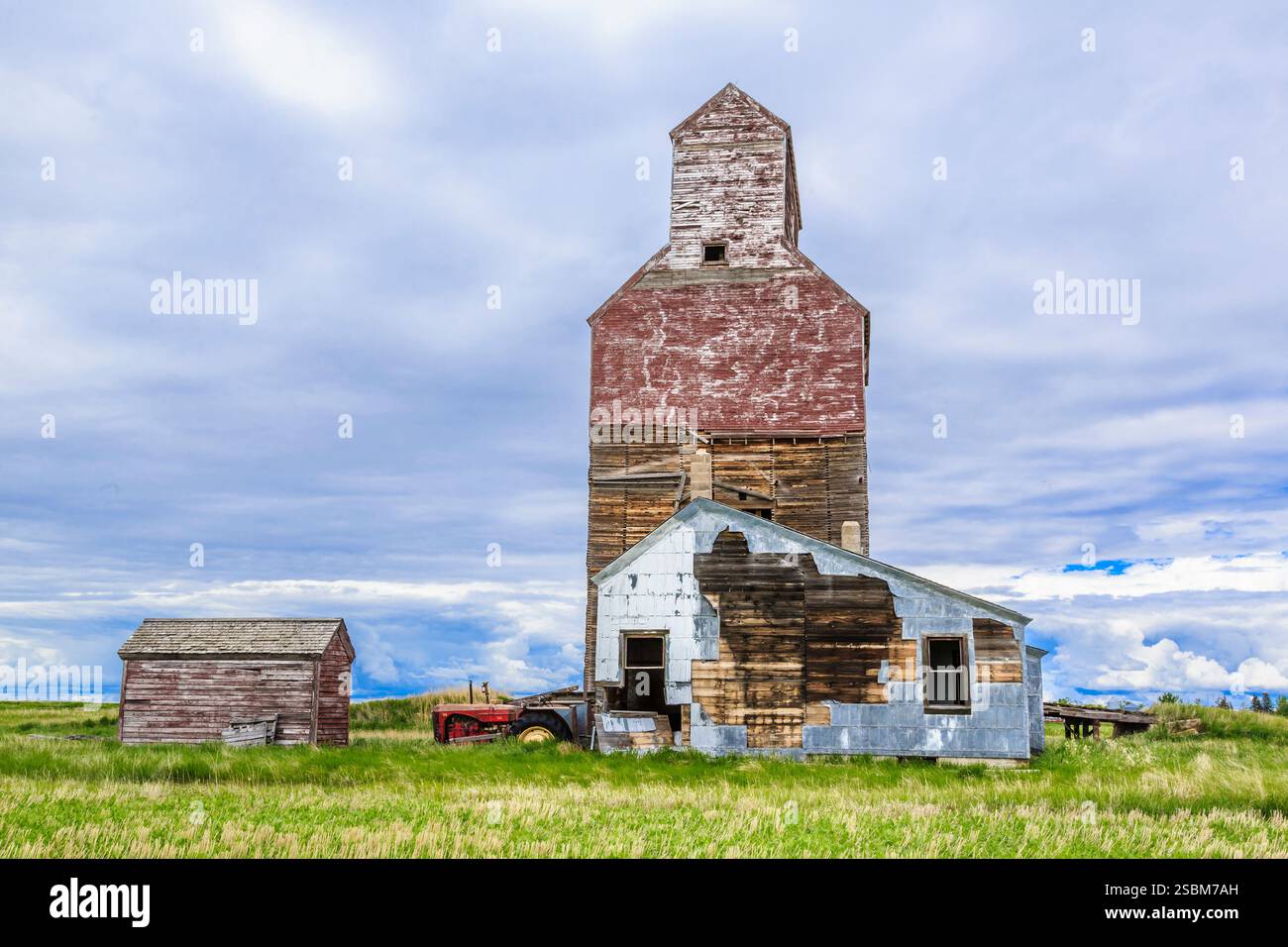 Rote Scheune und ein weißes Haus sind auf einem Feld. Die Scheune ist alt und das Haus auch alt Stockfoto