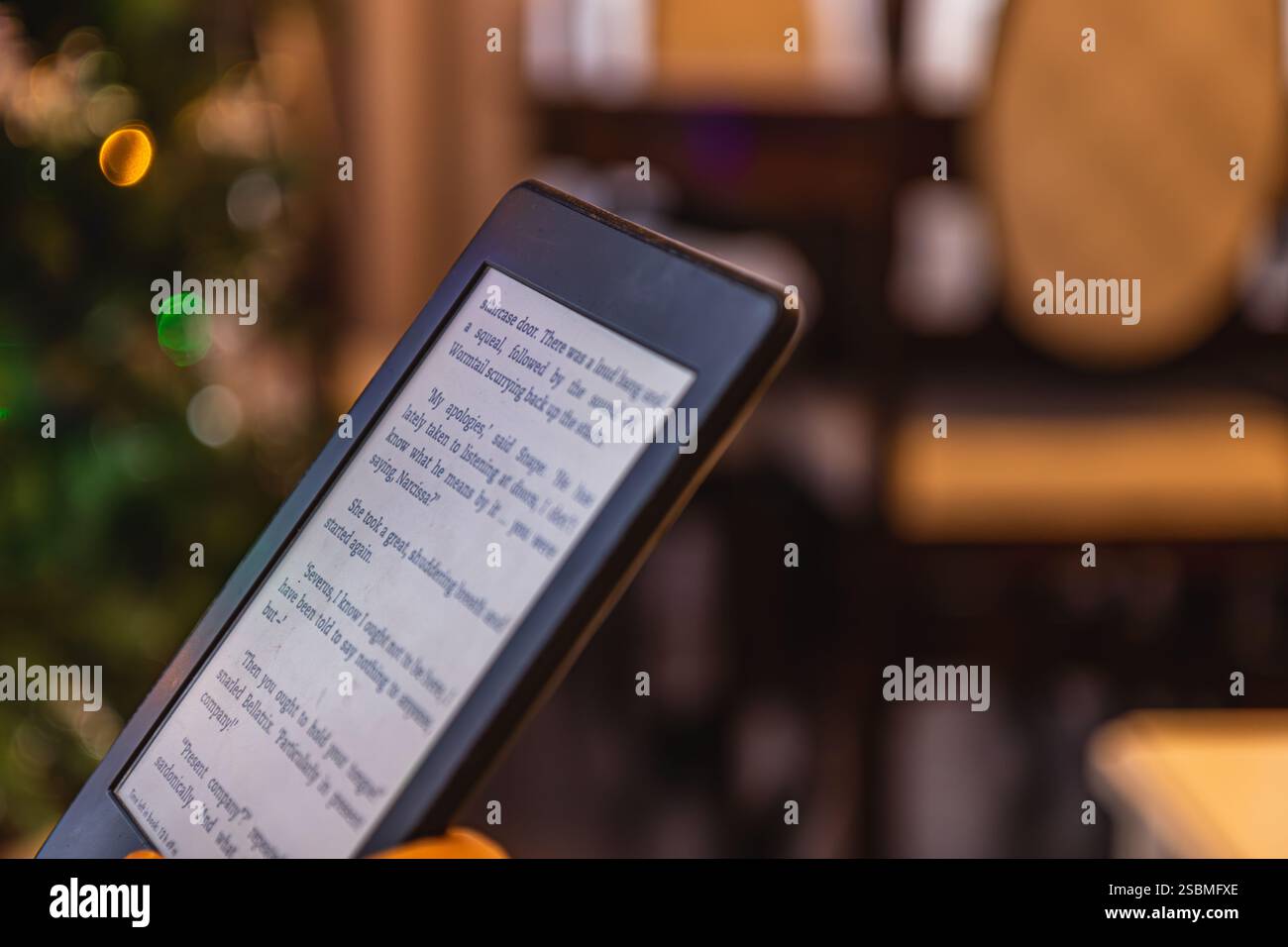 Eine Person liest ein E-Book, umgeben von einer gemütlichen Atmosphäre mit warmem Licht, die eine perfekte Umgebung für Entspannung und lea schafft Stockfoto