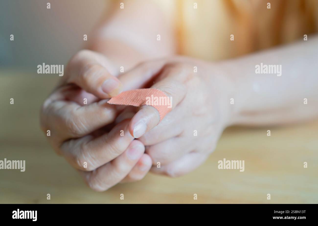 Schuss einer Frau, die zu Hause ihren verletzten Zeigefinger mit einem Gipsverband umwickelt. Konzept der Selbstversorgung nach häuslichen Unfallverletzungen Stockfoto