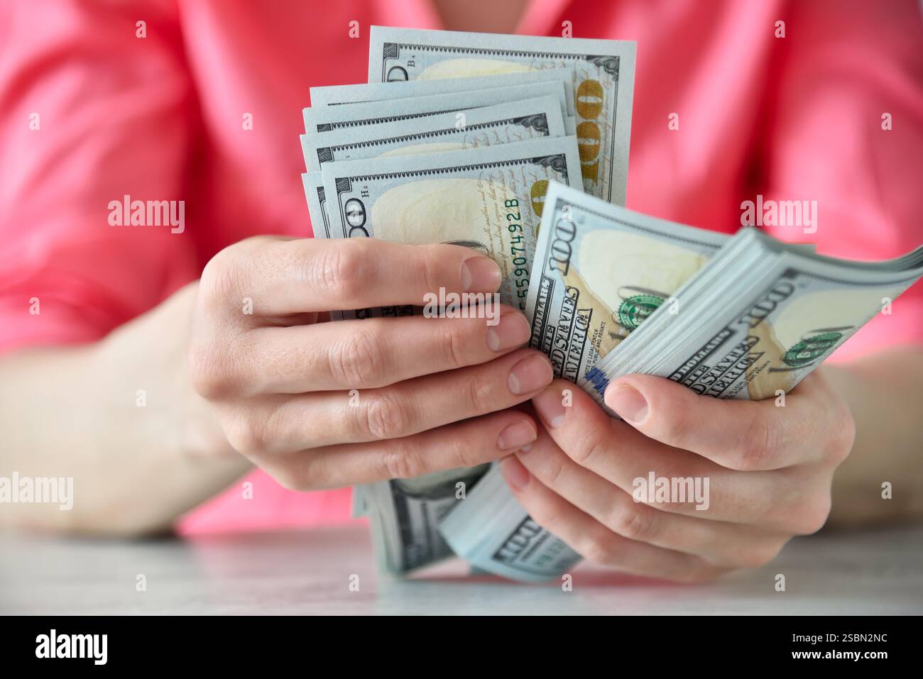 Geschäftsfrau, die am Tisch Dollar zählt. Finanzieller Erfolg und Geschäftskonzept. Nahaufnahme Stockfoto