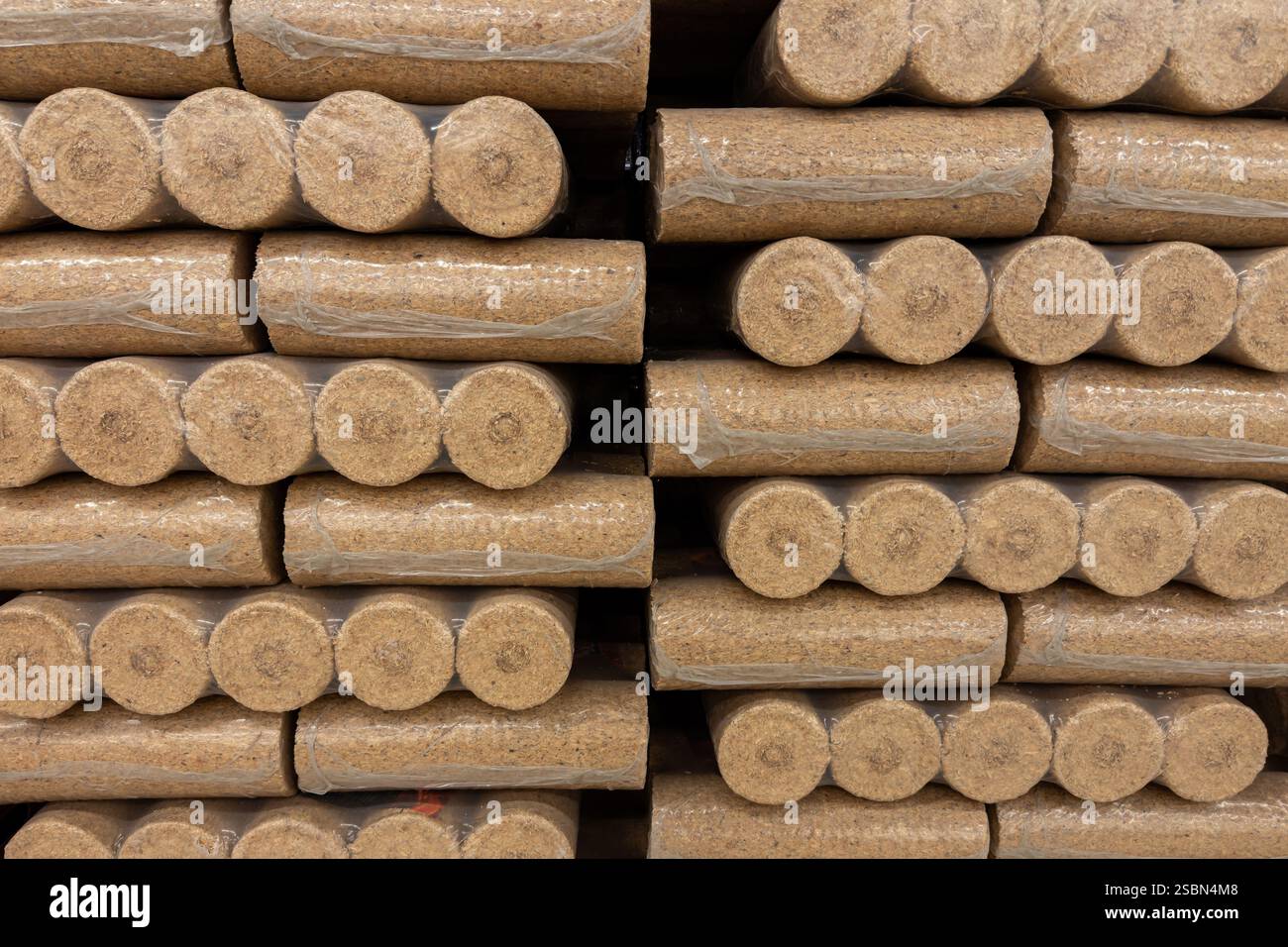 Ordentlich gestapelte, komprimierte Holzpellets werden in einem Lager gelagert. Die Pellets sind zylindrisch und dicht verpackt, bereit für den Vertrieb oder die Verwendung in Heizungen Stockfoto