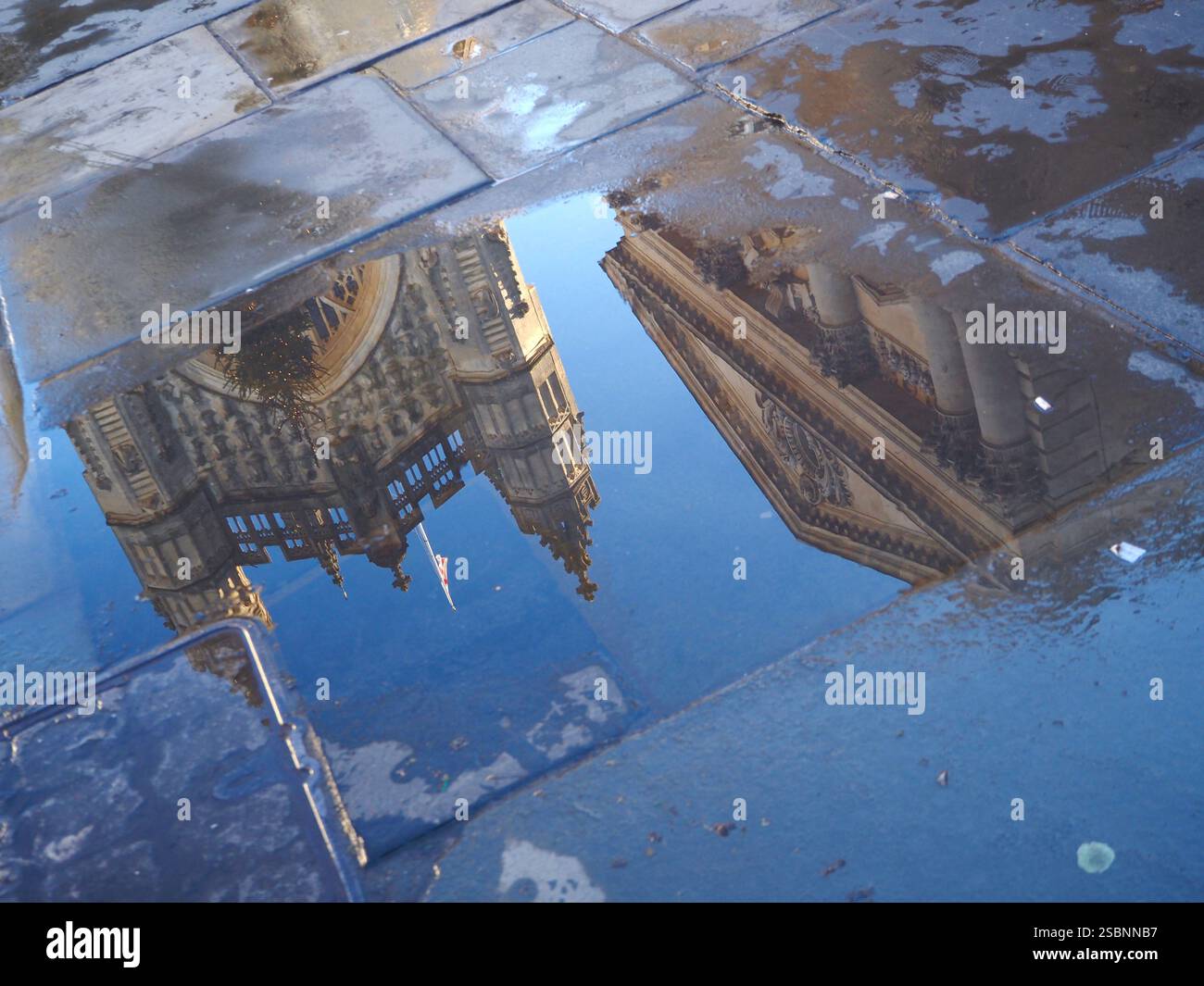 Bath Abbey und das Gebäude der römischen Bäder spiegeln sich in nassen Pflastersteinen mit blauem Himmel wider. Stockfoto