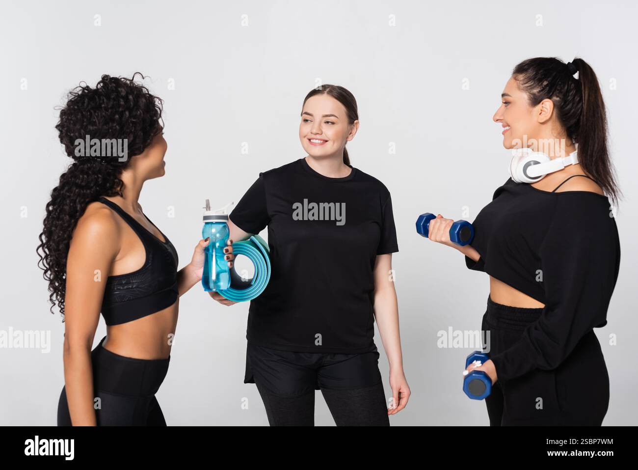 Drei starke und fitte Frauen teilen Motivation und Lachen, während sie gemeinsam in einem Studio trainieren. Stockfoto
