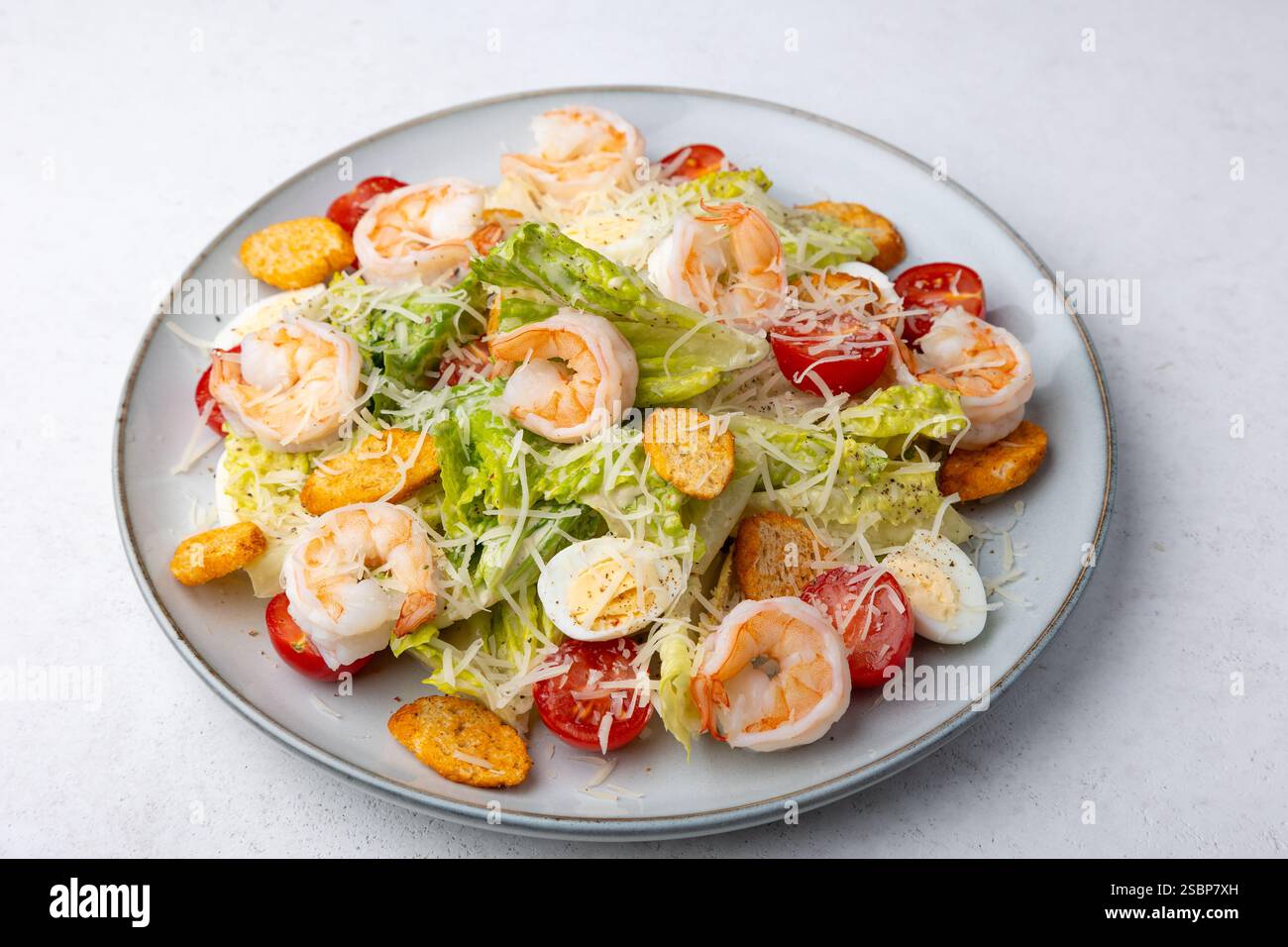 Caesar Salat mit Tigergarnelen, Kirschtomaten, Croutons, Parmesan, Wachteleiern und Römersalat. Traditionelles amerikanisches Gericht. Nahaufnahme, Auswahl Stockfoto