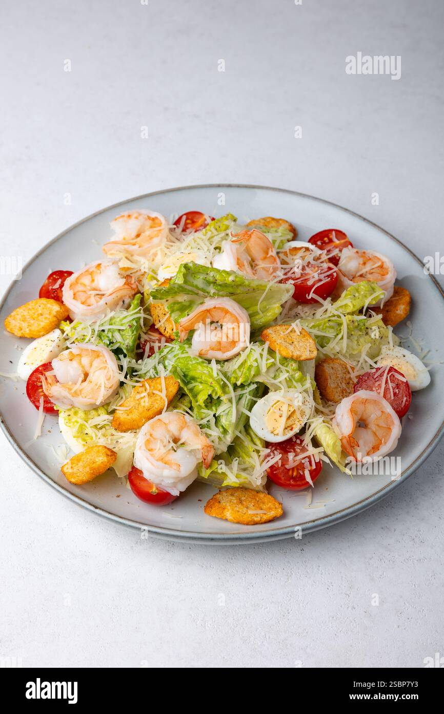 Caesar Salat mit Tigergarnelen, Kirschtomaten, Croutons, Parmesan, Wachteleiern und Römersalat. Traditionelles amerikanisches Gericht. Nahaufnahme, Auswahl Stockfoto