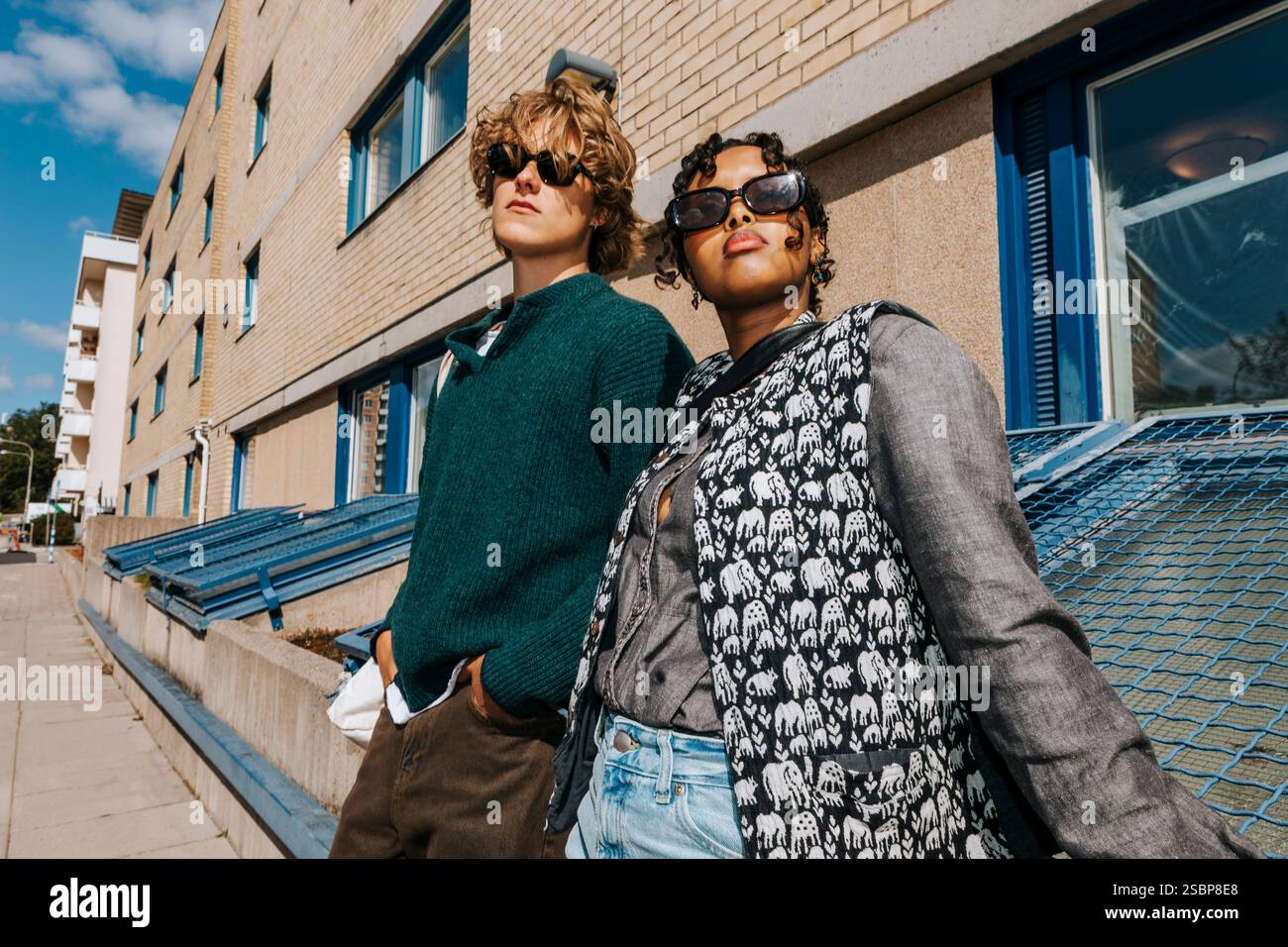 Modische junge Studenten, die eine Sonnenbrille tragen und auf dem College-Campus posieren Stockfoto