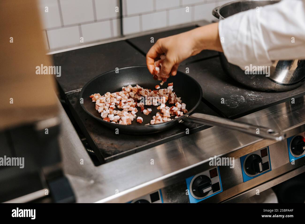 Weibliche Köchin kocht in der Küche des Restaurants Fleisch in der Pfanne auf dem Herd Stockfoto
