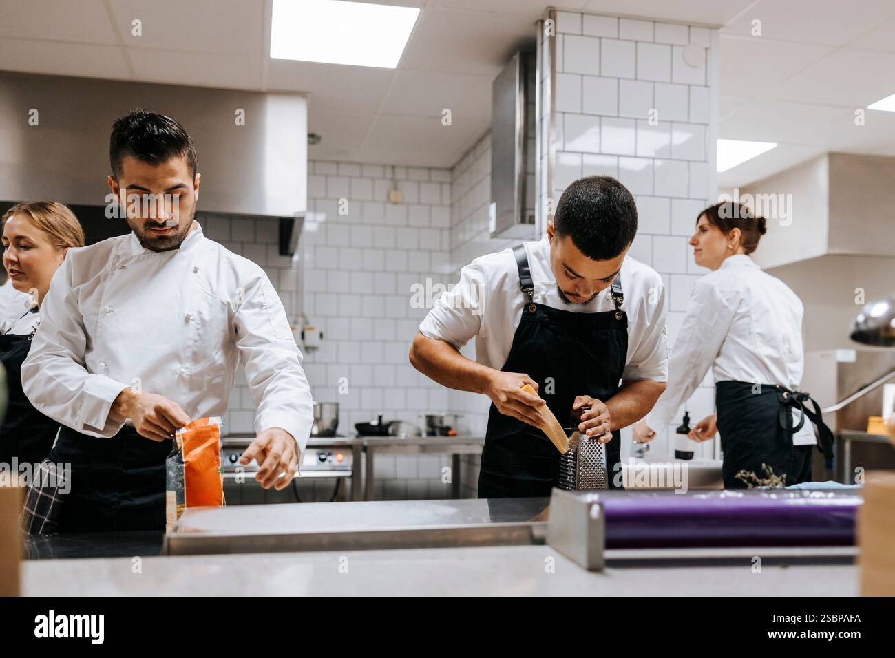 Junge männliche Köche, die in der Küche im Restaurant arbeiten Stockfoto