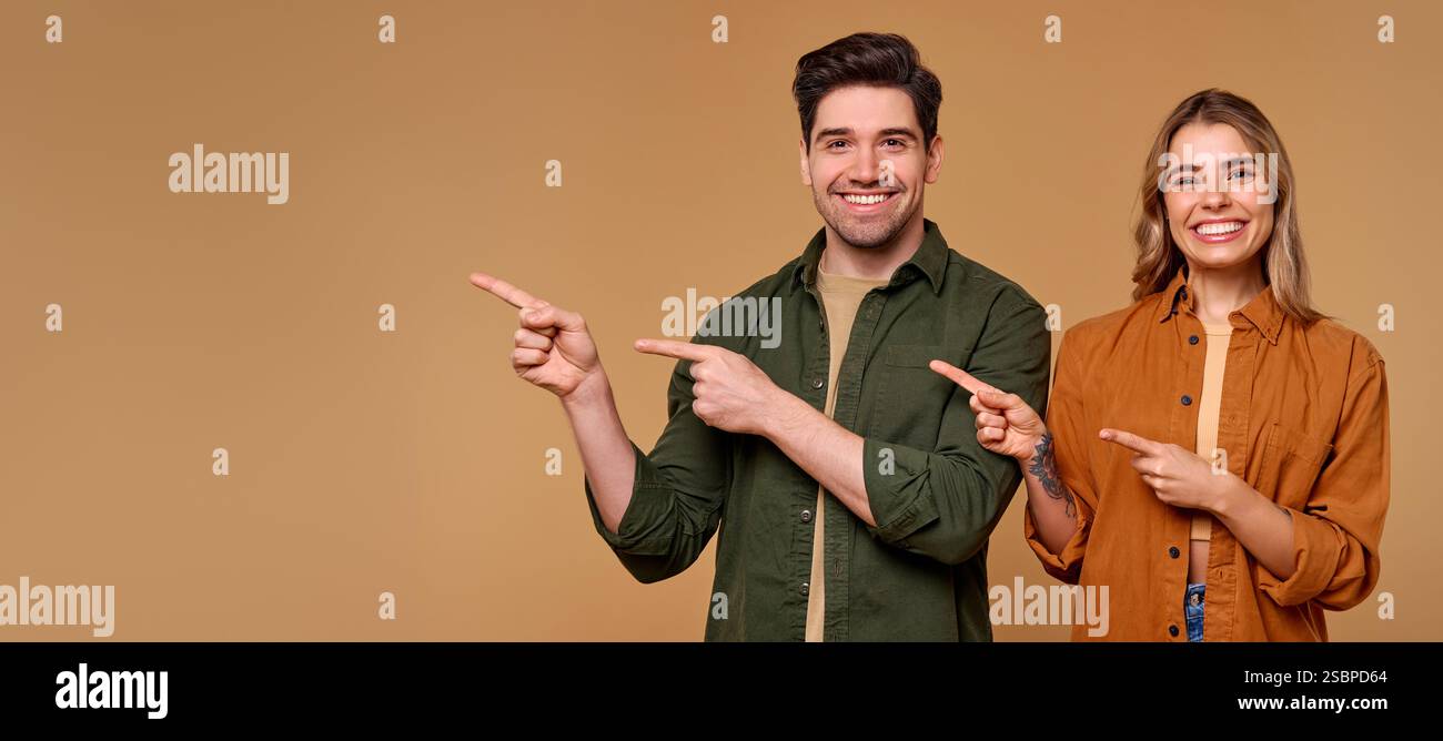 Ein fröhliches Paar drückt seine Begeisterung durch lebhafte Gesten aus, zeigt und lächelt sich gegenseitig an. Dieses Image eignet sich hervorragend für Werbeaktionen, Marketing und e Stockfoto