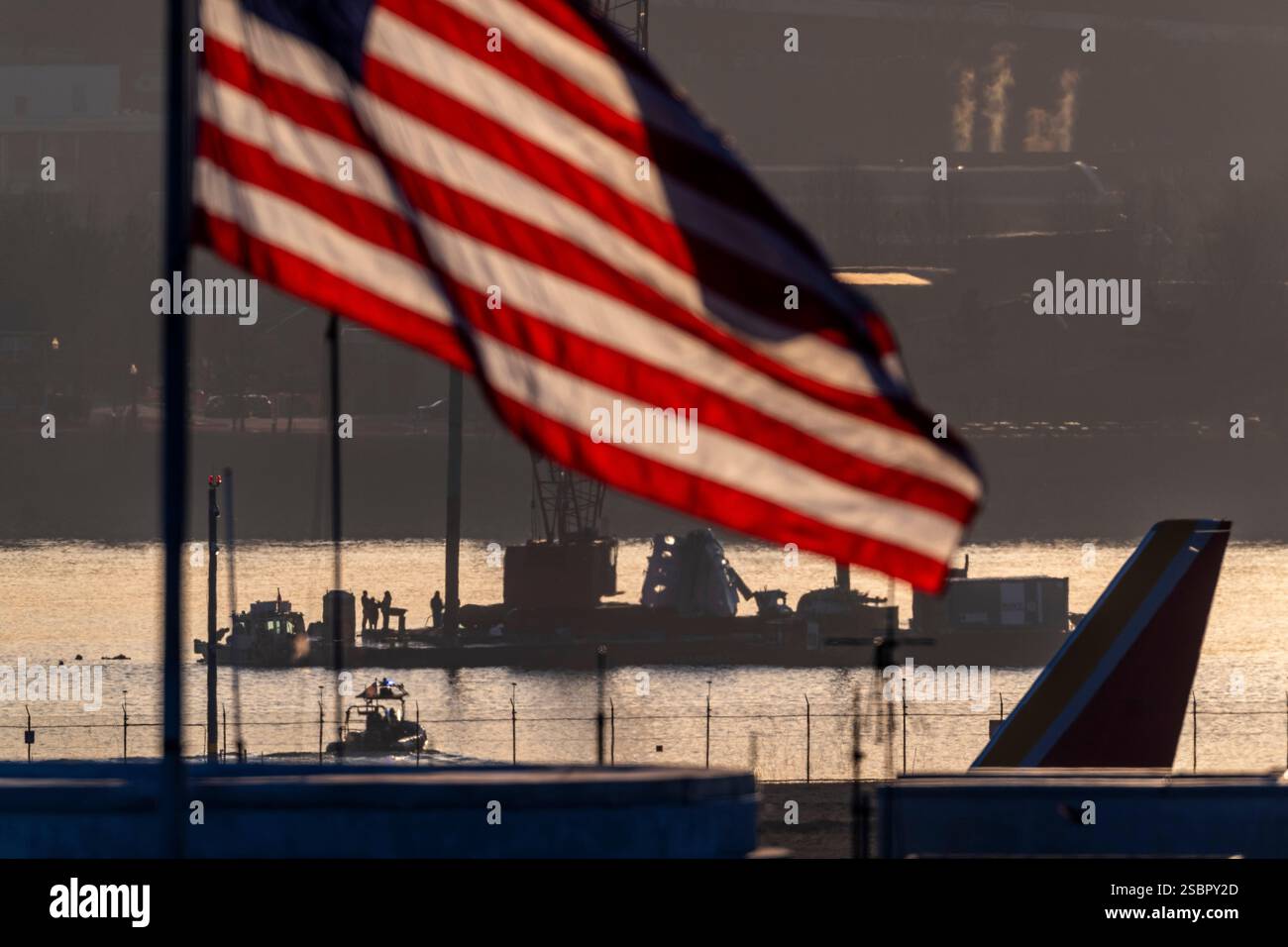 An airplane passes, right, as salvage crews work near the wreckage site ...