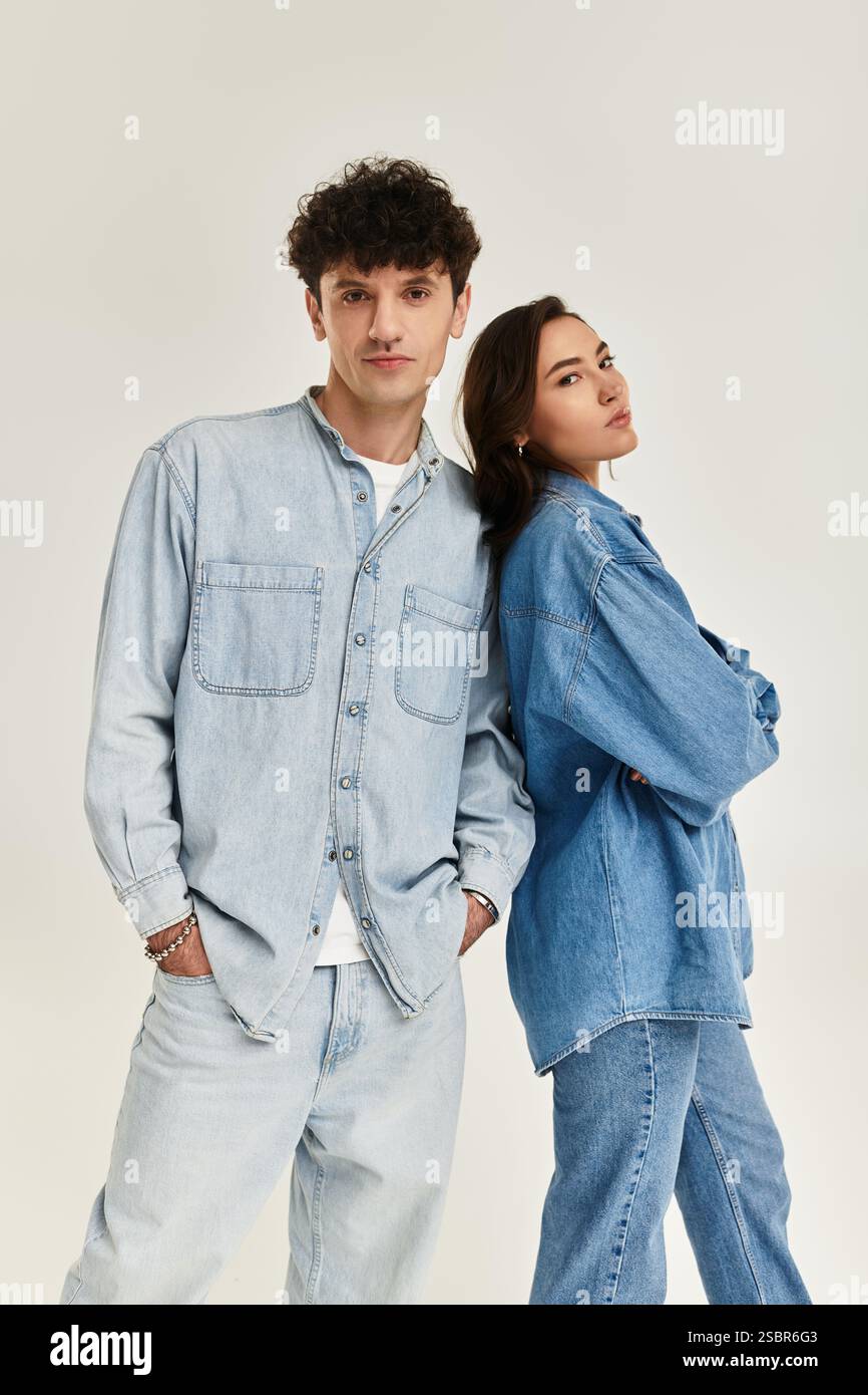 Zwei junge Individuen präsentieren trendige Denim-Outfits in einem hellen, stilvollen Raum. Stockfoto