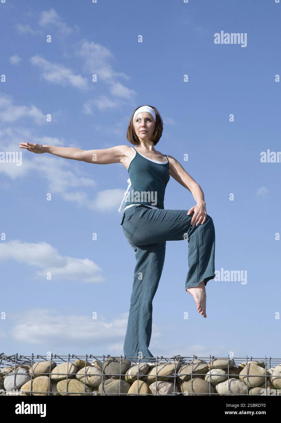 Frau macht Yoga-Übungen in oberem Teil einer Steinmauer Stockfoto