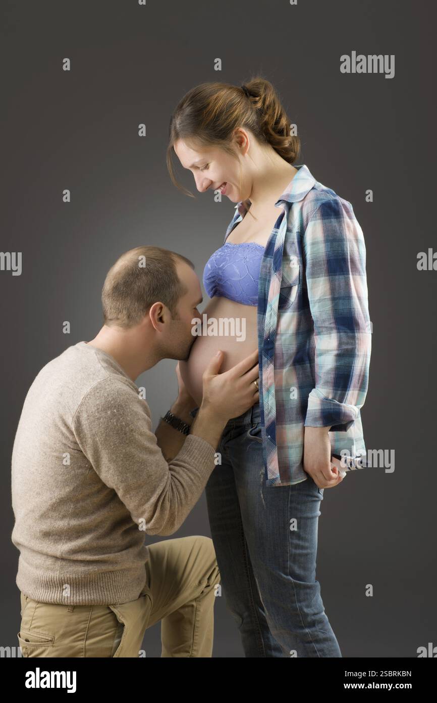 Porträt eines glücklichen schwangeren Paares auf grauem Hintergrund Stockfoto