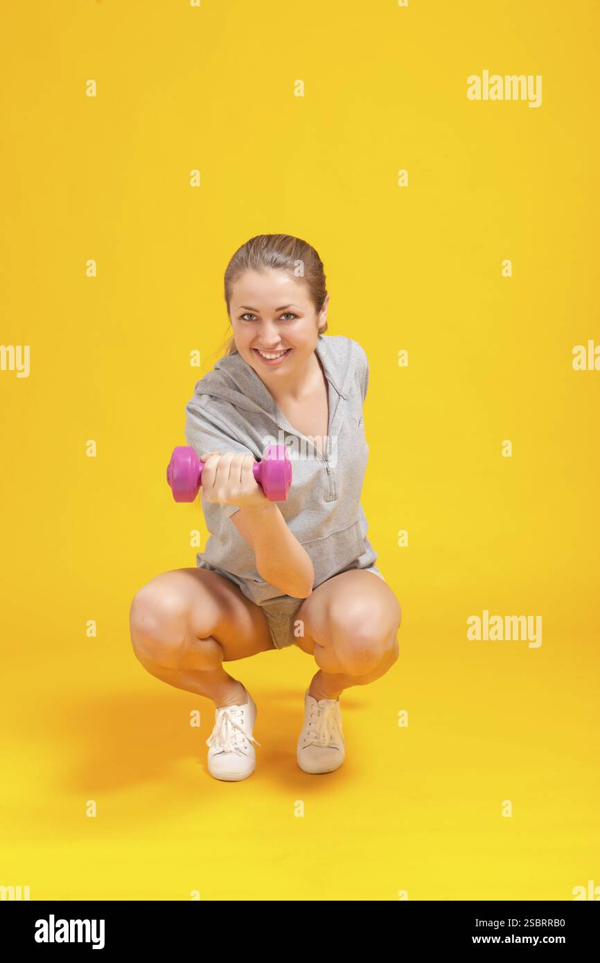 Junge blonde Fitness-Frau auf gelbem Hintergrund Stockfoto