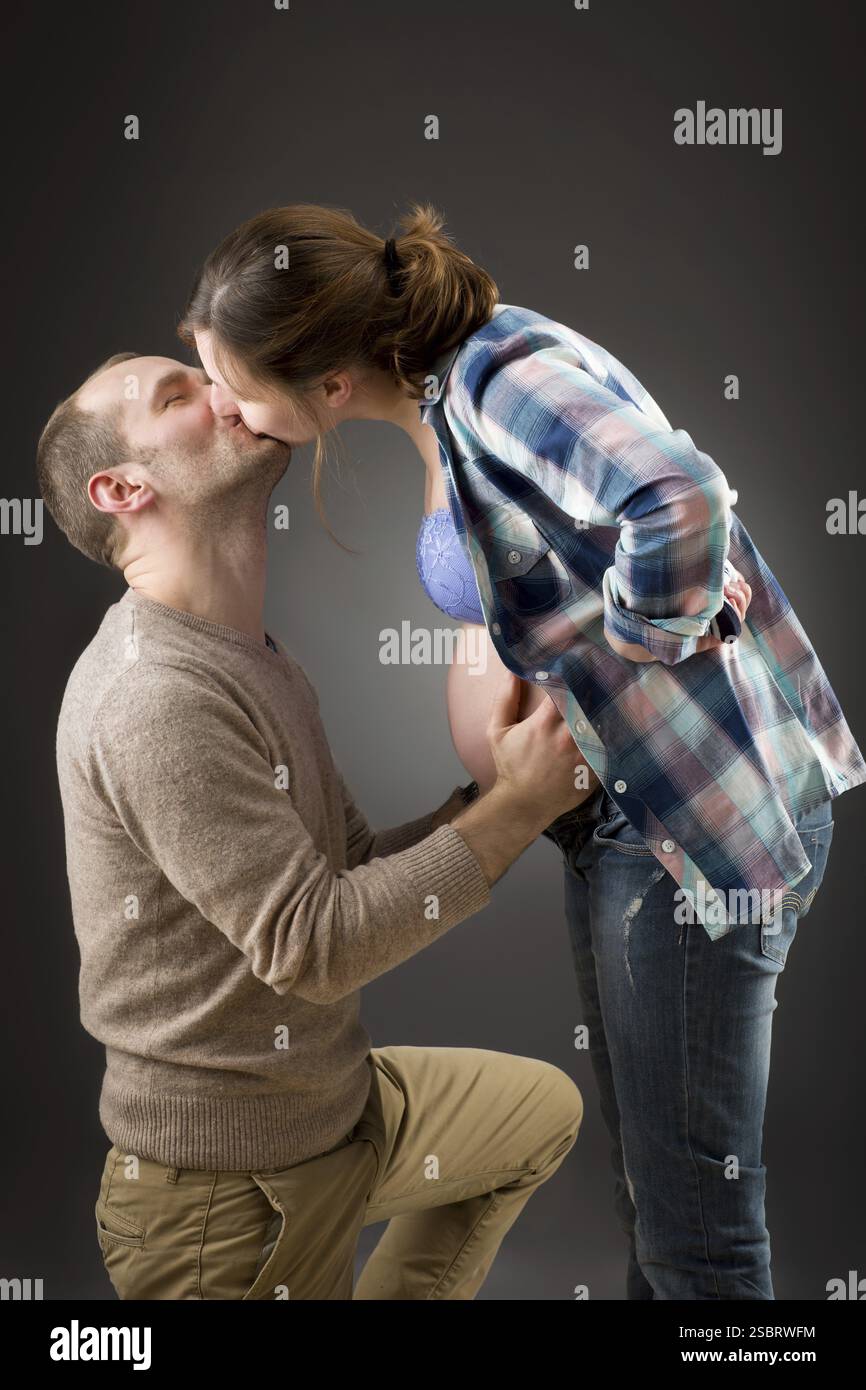 Porträt eines glücklichen schwangeren Paares auf grauem Hintergrund Stockfoto