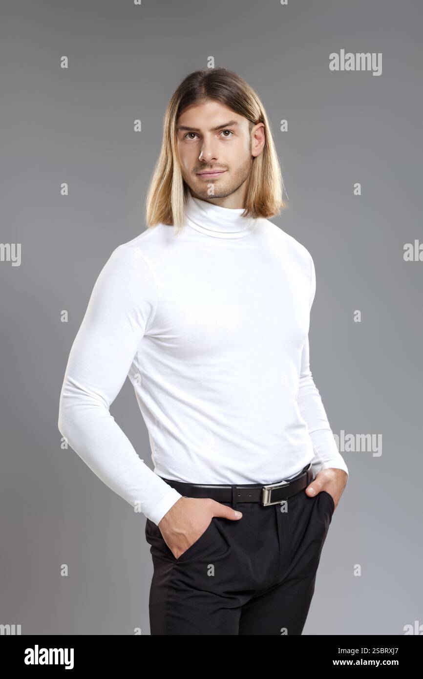 Männermode, Schönheitskonzept. Porträt eines jungen Mannes mit blonden Haaren, der auf grauem Hintergrund posiert. Klassischer STYLE. Studio-Aufnahme Stockfoto