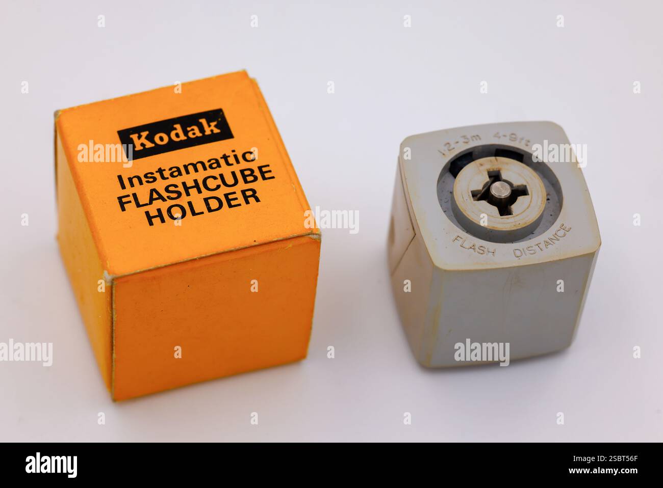 Kodak instamatic Blitzwürfelhalter mit original gelber Box. Unterseite des Halters. Retro-fotografische Filmkamera-Beleuchtungsausrüstung isoliert auf weiß Stockfoto